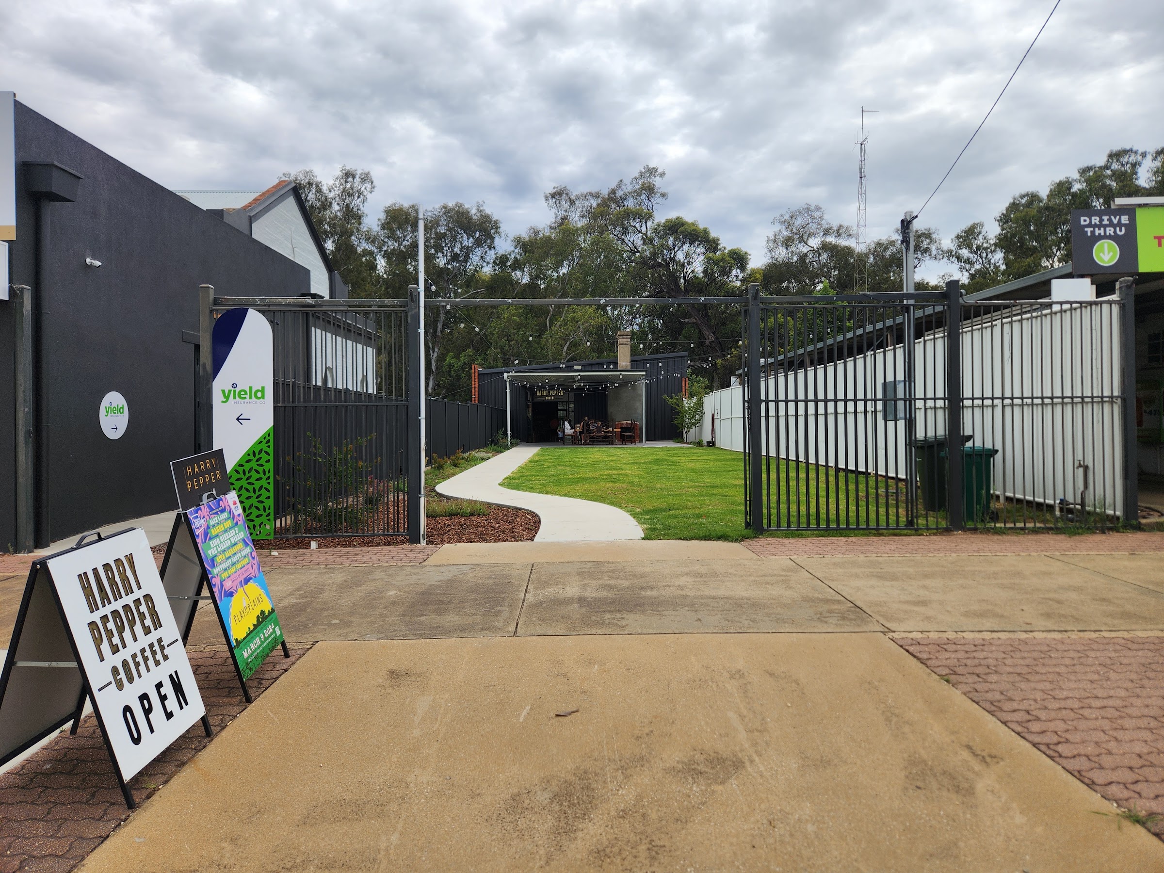 The gated entrance on End Street, with the Harry Pepper Coffee A frame sign and the lawn courtyard behind